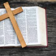 A wooden cross sits on top of an open  bible